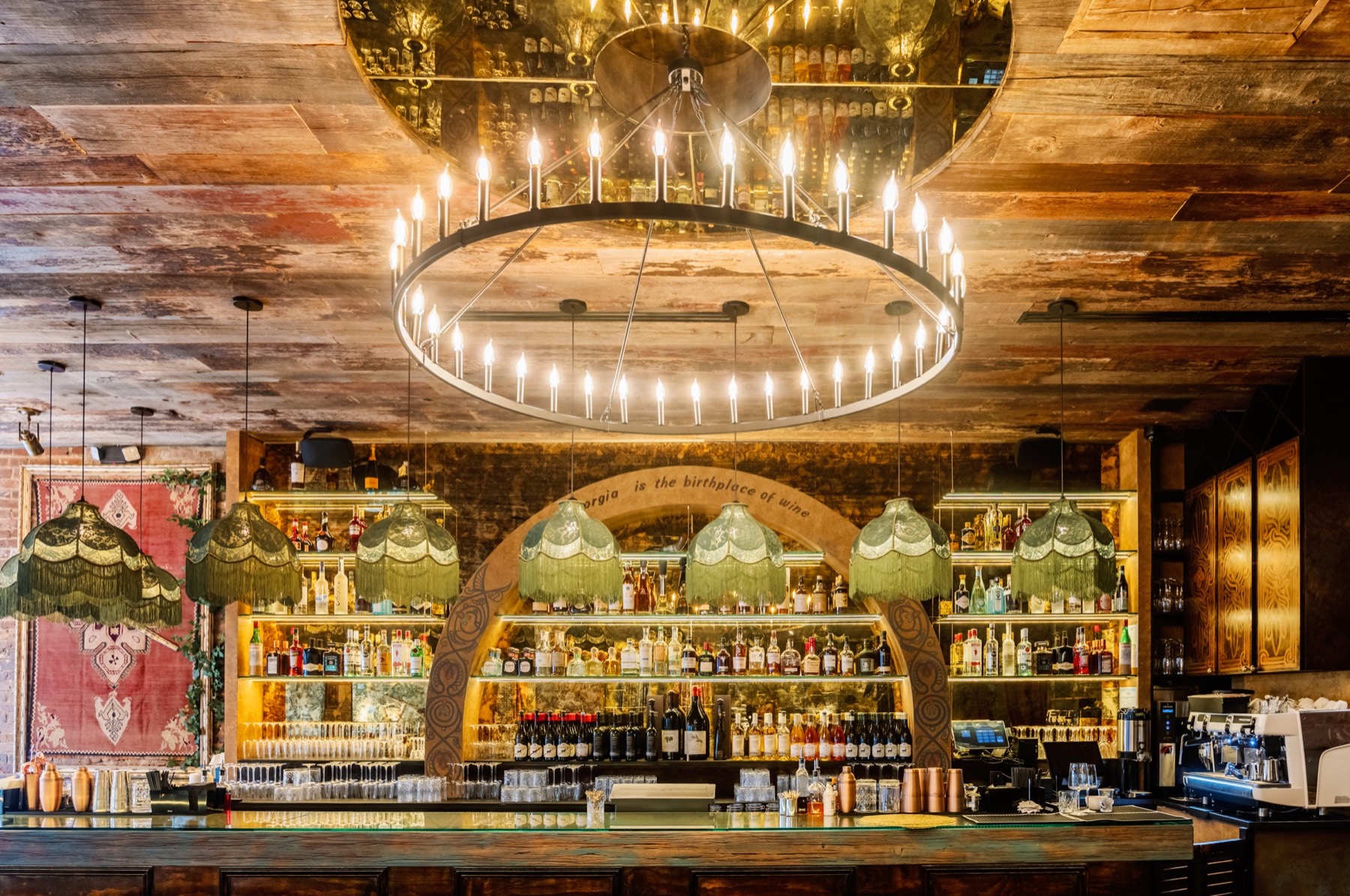The History Restaurant bar build-out in Hell's Kitchen with illuminated shelving, chandelier lighting, and custom wood ceiling work by BUILD IN NYC