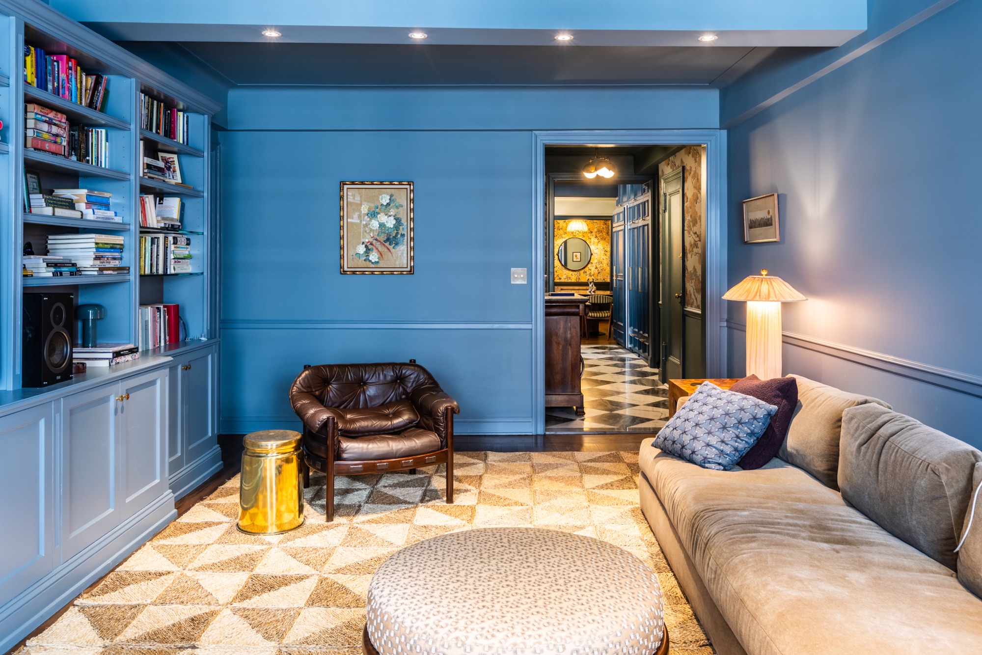 Blue residential lounge and library renovation with built-in shelving, warm lighting, and custom interior finishes by BUILD IN NYC
