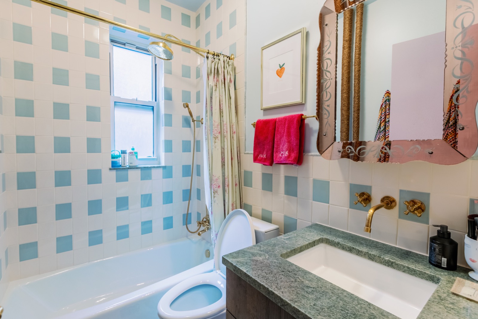 Bathroom with blue and white tile, brass fixtures, and green stone vanity