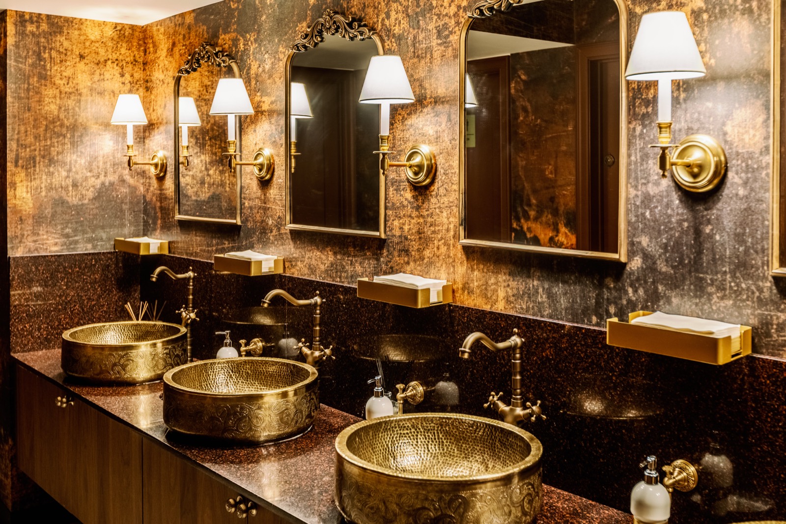 Brass vanity sinks with mirror and wall sconce lighting
