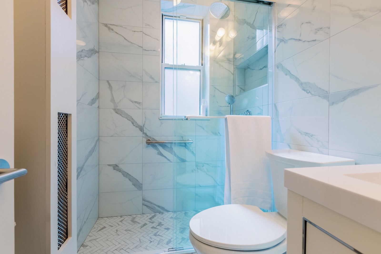 Bright bathroom with marble-look shower tile and glass enclosure