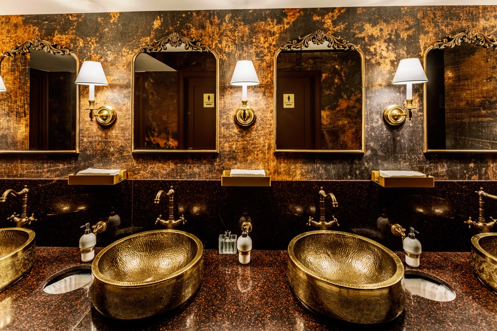 Luxury brass bathroom vanity sinks with framed mirrors and wall sconce lighting by Build in NYC