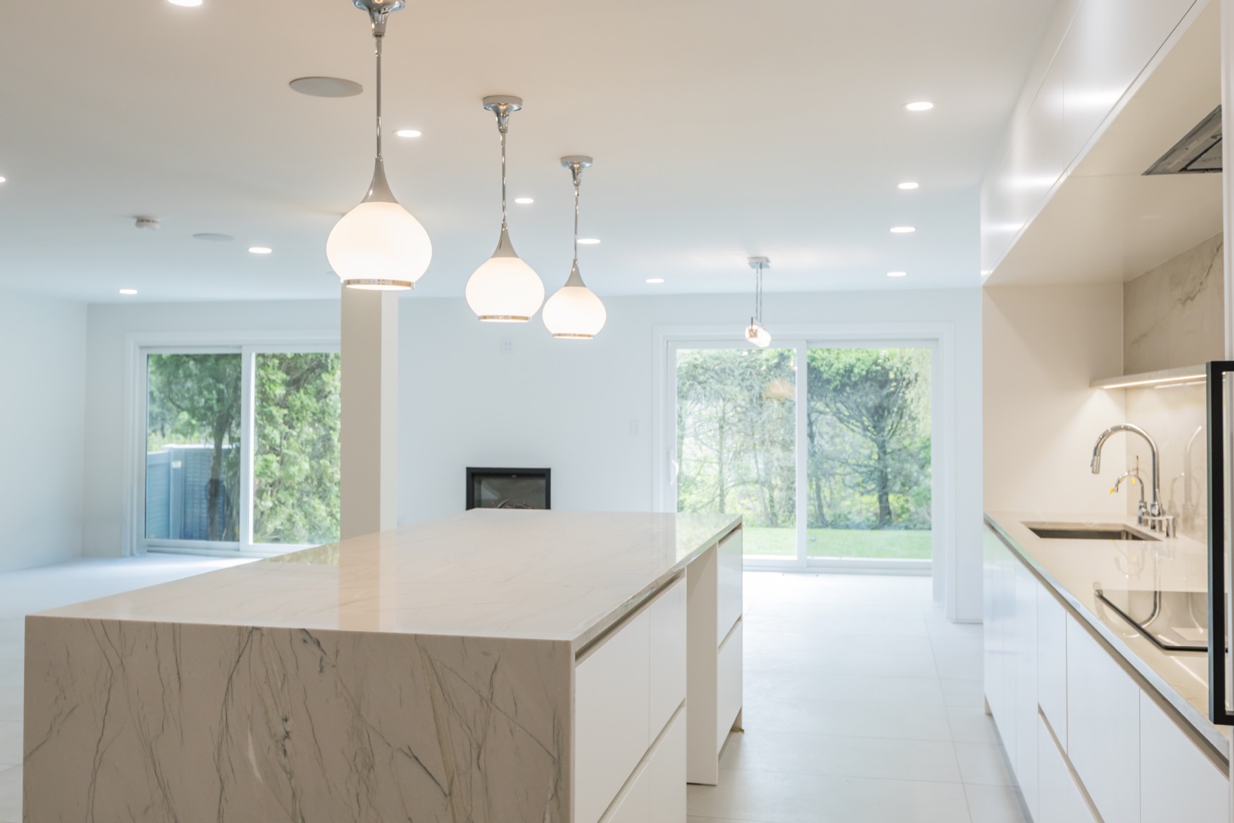 29 Fairway in Manhasset custom kitchen renovation with marble-look waterfall island, white cabinetry, and modern pendant lighting