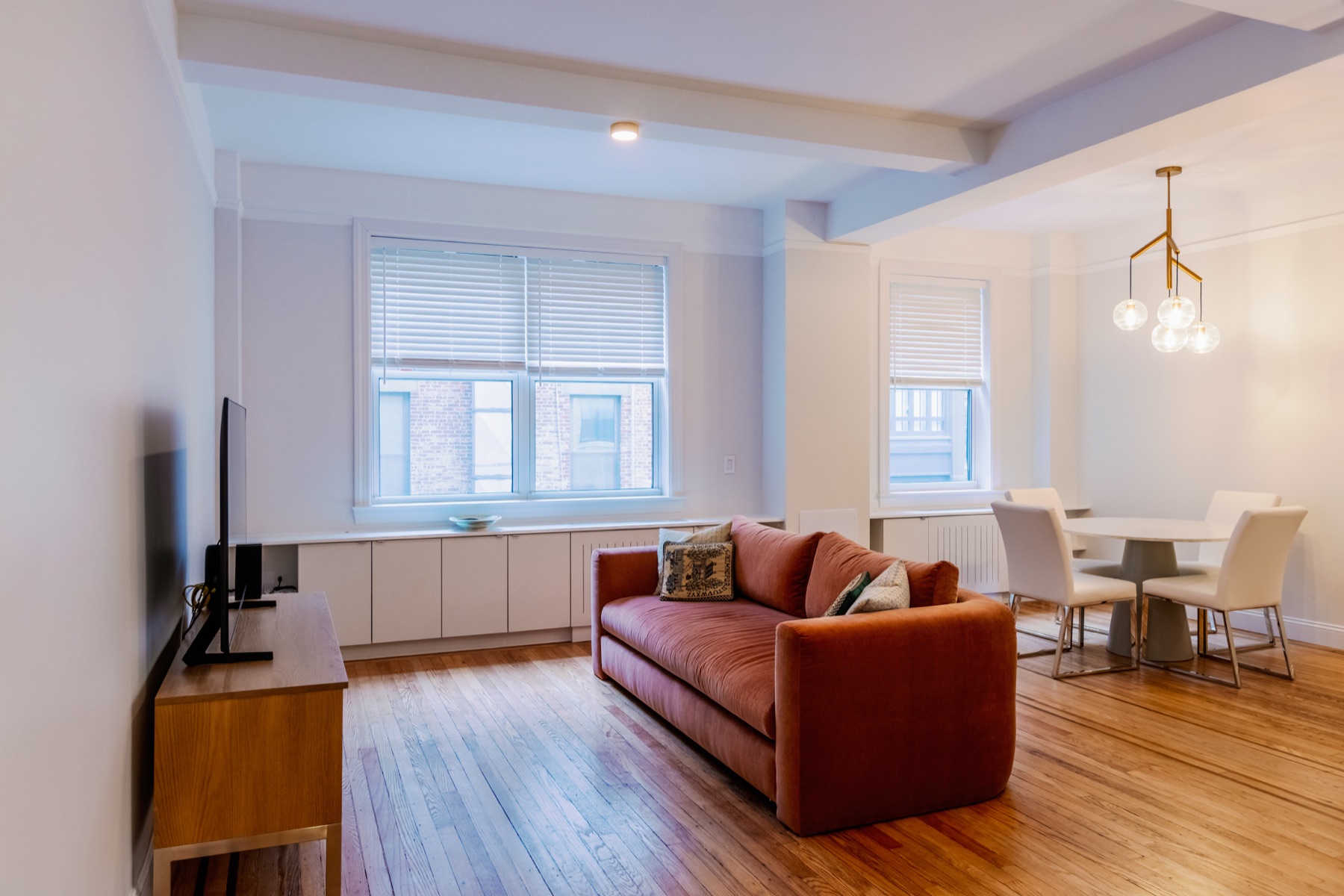 308 East 79th St full remodeling living and dining room with orange sofa and restored wood flooring